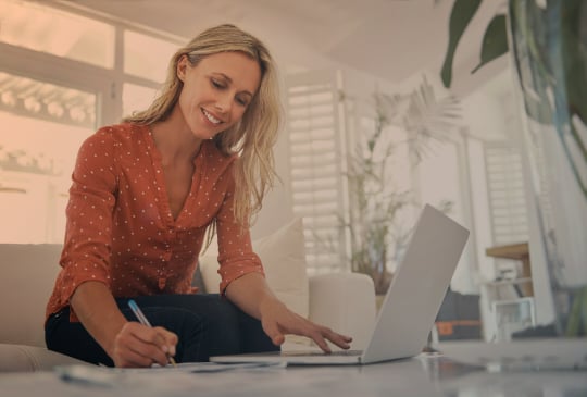 Frau an Laptop mit Stift in der Hand