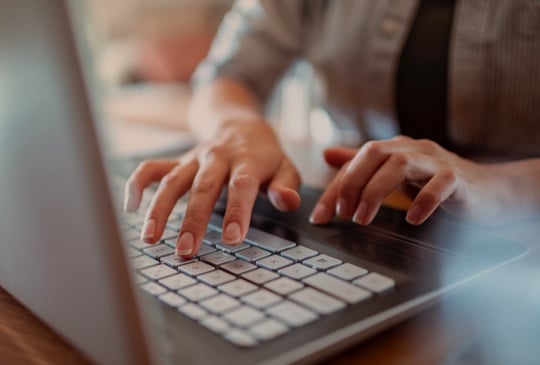 Person am Arbeiten an Laptop Tastatur 